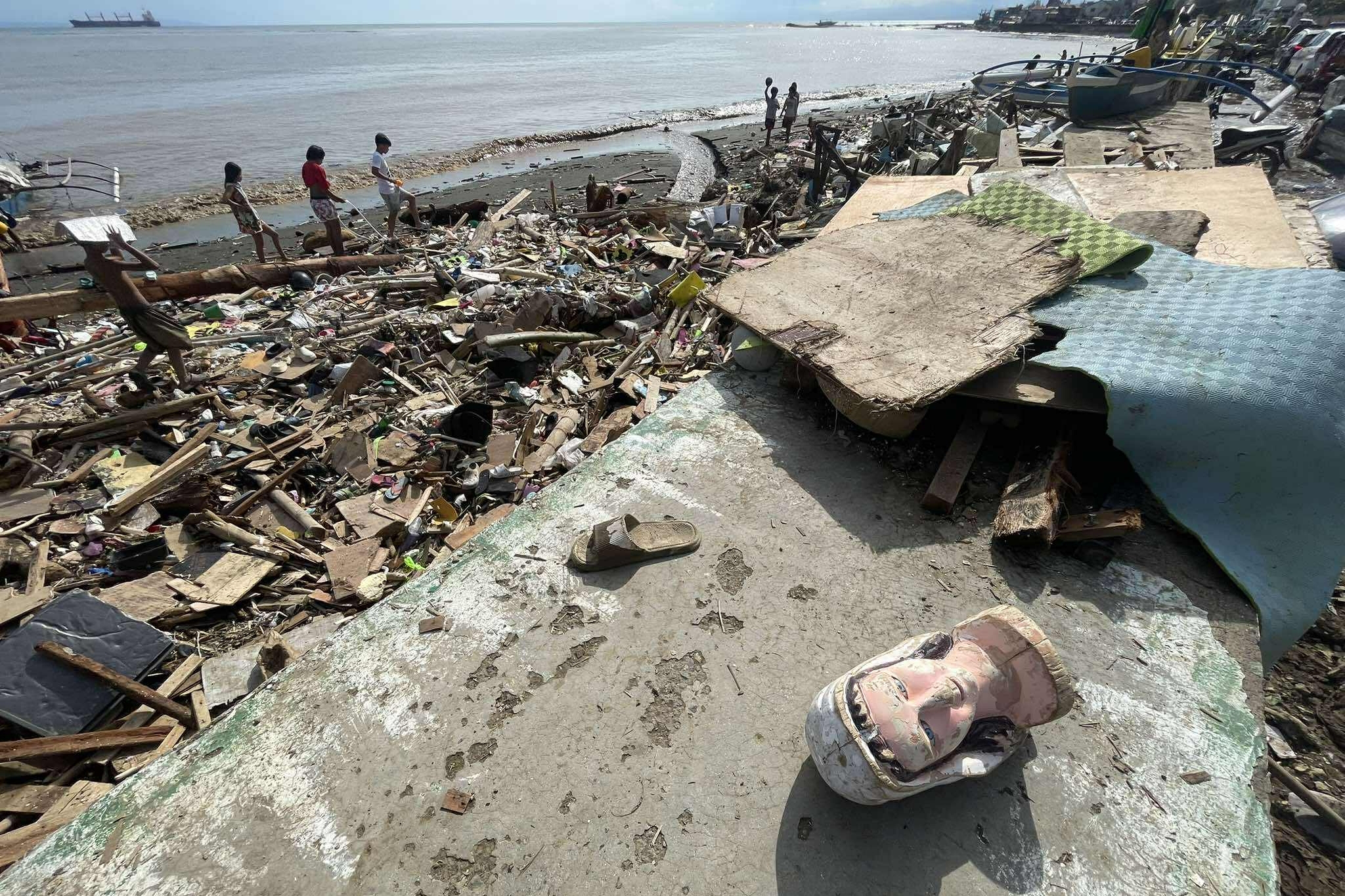 Residents walk along debris along a shoreline after Typhoon Kalmaegi caused devastation in communities at Talisay City, Cebu province, central Philippines, on Wednesday.